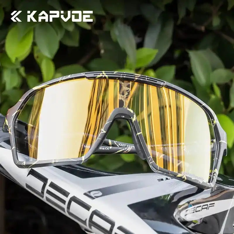 KAPVOE yellow-lens cycling sunglasses resting on a helmet. Features UV400 protection and a wide field of vision for outdoor sports.