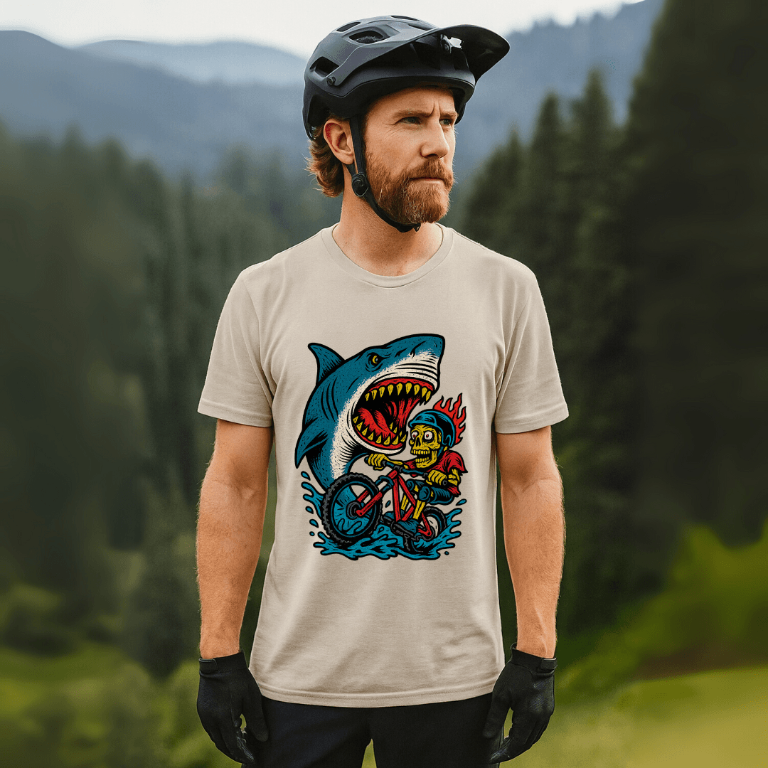Man modeling Shark Attack MTB Tee in beige with vivid shark and biker print. Lightweight men's mountain bike shirt for casual and active wear.