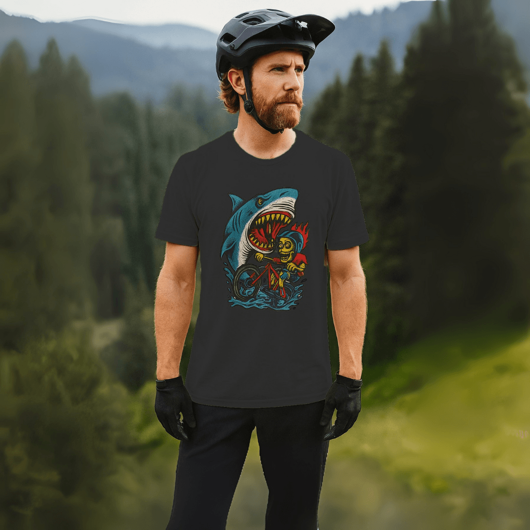 Man wearing Shark Attack MTB Tee in black, standing in a forested mountain area. Stylish CVC jersey shirt perfect for outdoor biking adventures.
