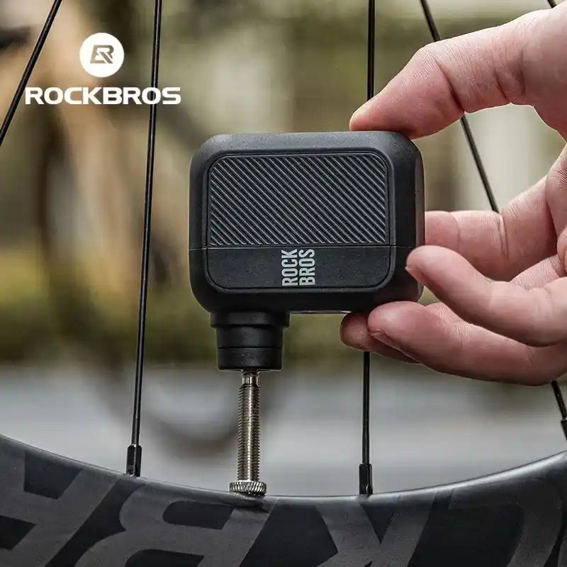 ROCKBROS Mini Electric Bike Pump 100PSI in use inflating a bicycle tire. Compact and handheld for easy outdoor cycling maintenance.