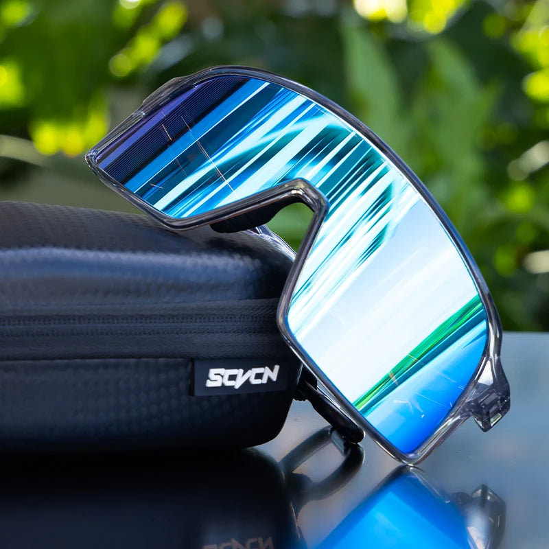 SCVCN cycling glasses with blue-green mirrored lenses resting on a black case, combining impact resistance and windproof design for cyclists.